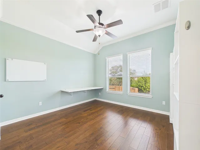 an empty room with wooden floor fan and windows