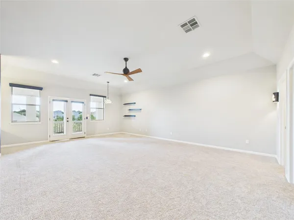 an empty room with chandelier fan and windows