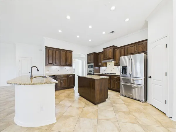 a large kitchen with stainless steel appliances granite countertop a sink refrigerator and cabinets