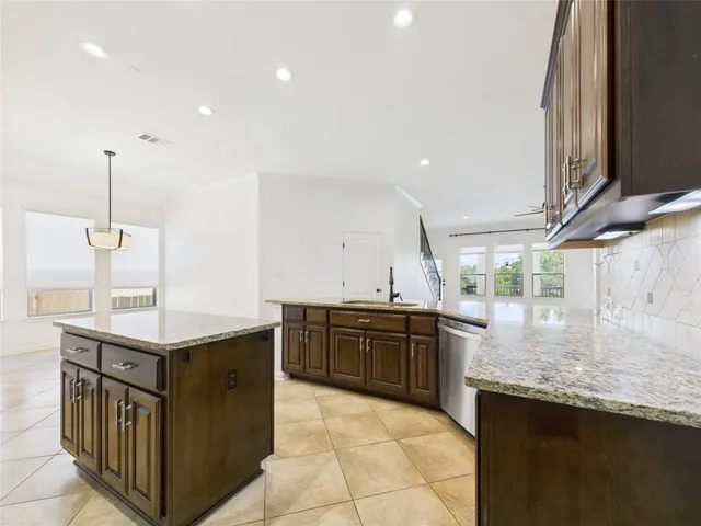 a kitchen with stainless steel appliances granite countertop a sink a stove and a wooden floors