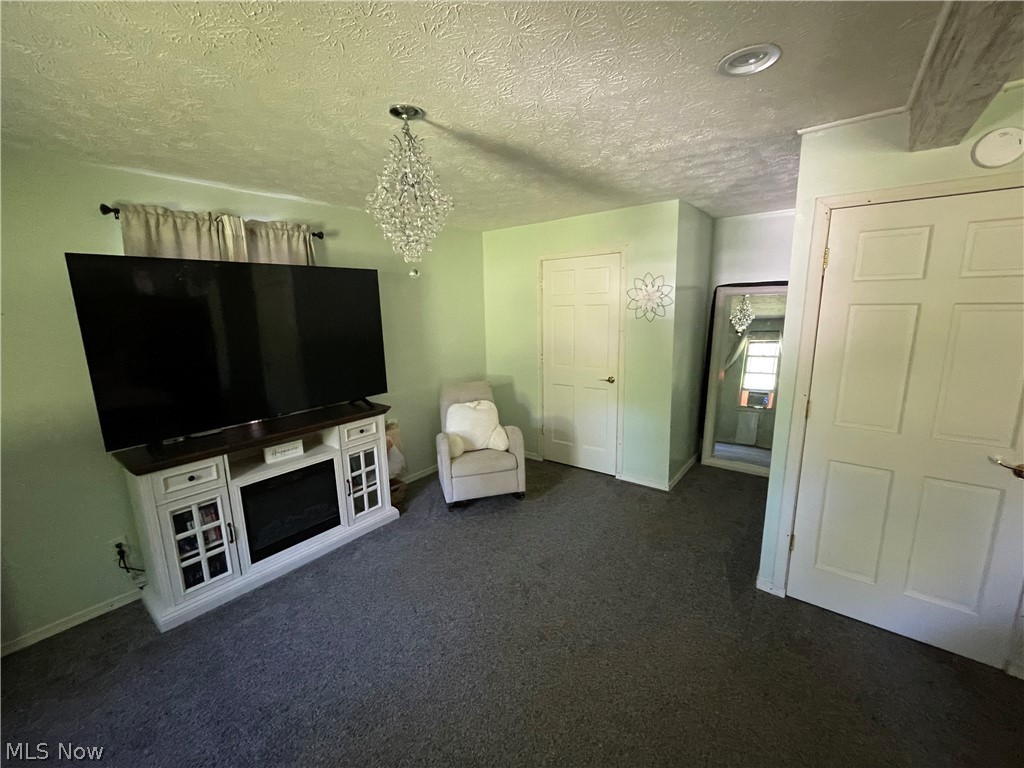 54544 Mt Victory Road Powhatan Point, OH 43942 - Photo 20 of 43 Unfurnished room featuring a textured ceiling, an inviting chandelier, and dark carpet
