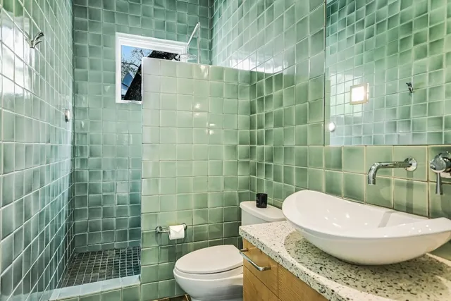 a bathroom with a granite countertop toilet a sink and shower