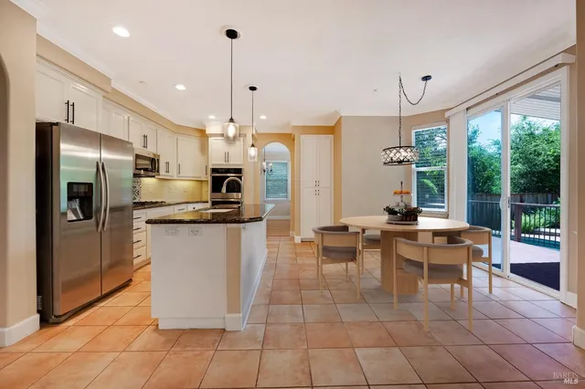 a kitchen with stainless steel appliances kitchen island granite countertop a refrigerator a oven a sink a counter top and a view of living room with furniture