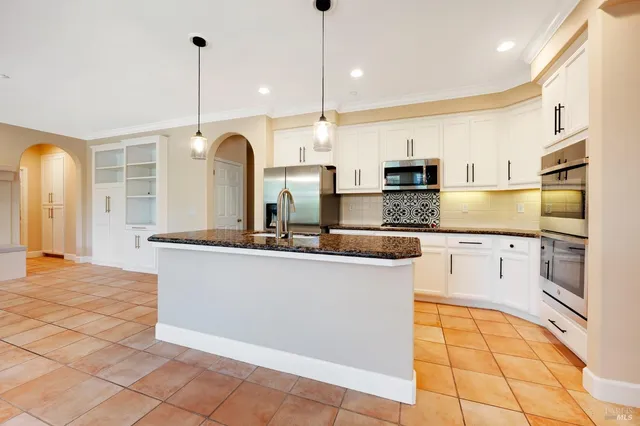 a kitchen with stainless steel appliances granite countertop a sink a oven and a refrigerator