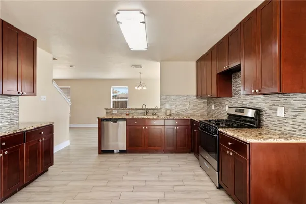 a large kitchen with stainless steel appliances granite countertop a stove a sink dishwasher and a microwave oven with cabinets