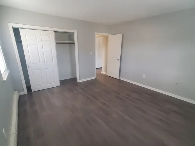 a view of an empty room with wooden floor and closet