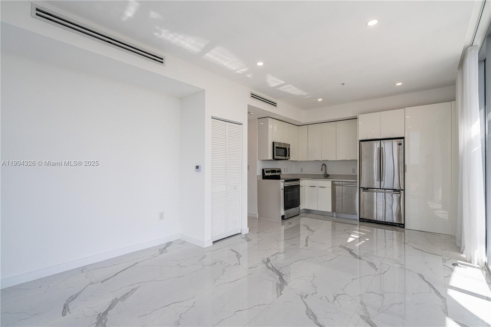8425 Crespi Boulevard, Unit 404 Miami Beach, FL 33141 - Photo 6 of 21 a kitchen with white cabinets and stainless steel appliances