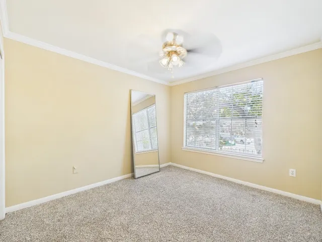 an empty room with a chandelier fan and windows