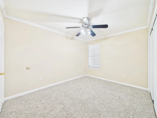 an empty room with windows and ceiling fan