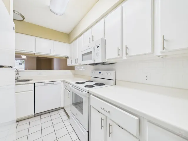 a kitchen with granite countertop white cabinets and white appliances