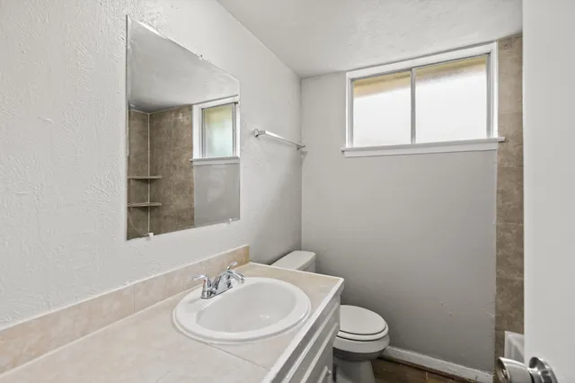 a bathroom with a sink a toilet and a window