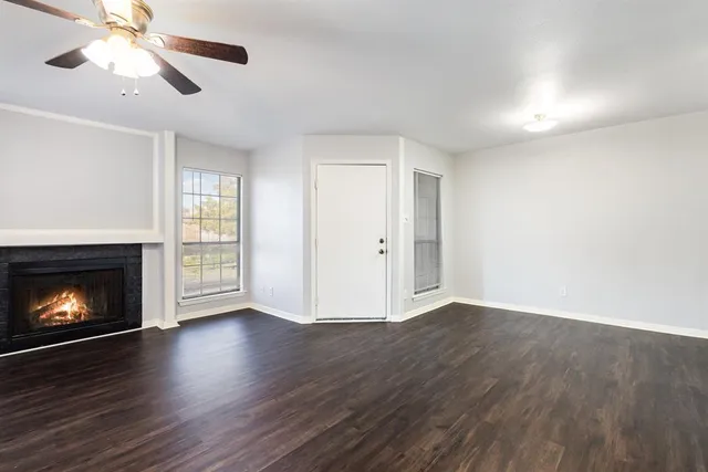 a view of an empty room with wooden floor fireplace and a window