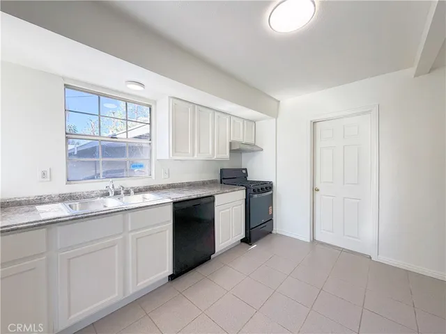 a kitchen with granite countertop a sink white cabinets and stainless steel appliances