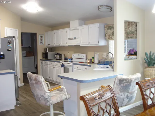 a kitchen with stainless steel appliances granite countertop a sink a stove a refrigerator and cabinets with wooden floor