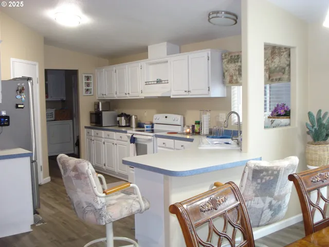 a kitchen with stainless steel appliances granite countertop a sink a stove a refrigerator and cabinets with wooden floor