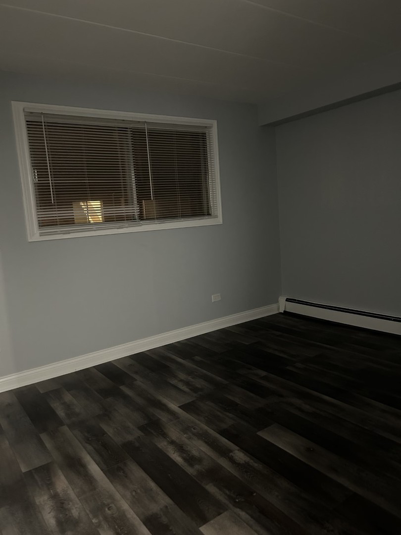 10440 Ridgeland Avenue, Unit 5 Chicago Ridge, IL 60415 - Photo 17 of 22 a view of an empty room with wooden floor and a window