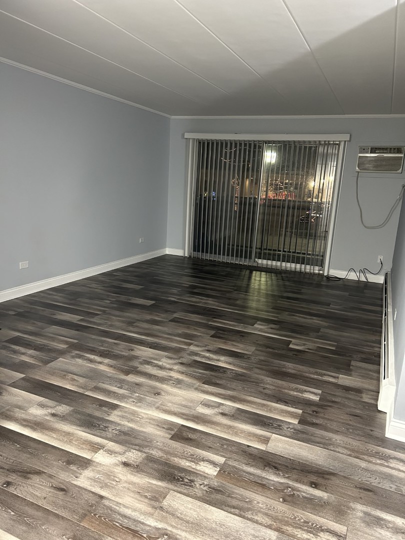 10440 Ridgeland Avenue, Unit 5 Chicago Ridge, IL 60415 - Photo 4 of 22 a view of an empty room with wooden floor and a window