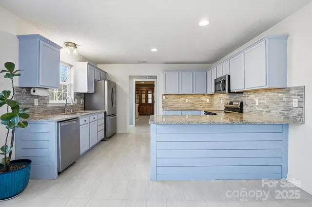 a kitchen with stainless steel appliances granite countertop a stove a sink and a refrigerator