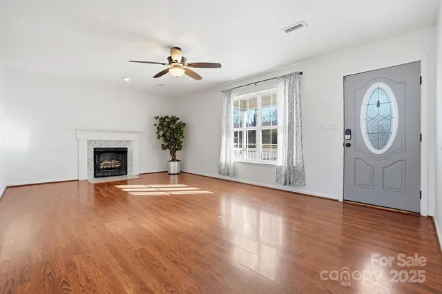 an empty room with wooden floor a ceiling fan and a fireplace