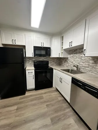 a kitchen with granite countertop a refrigerator stove top oven and sink