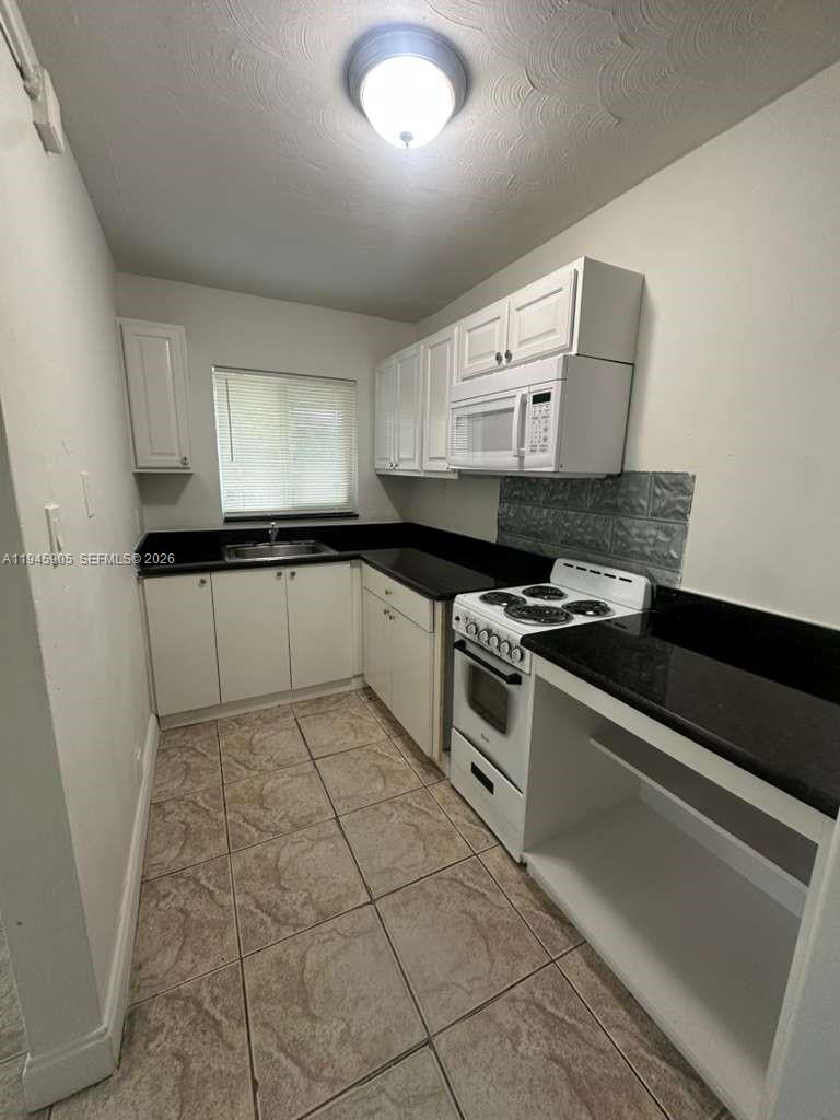 6321 Pembroke Road, Unit 6 Hollywood, FL 33023 - Photo 5 of 11 a kitchen with granite countertop a stove a sink and a microwave