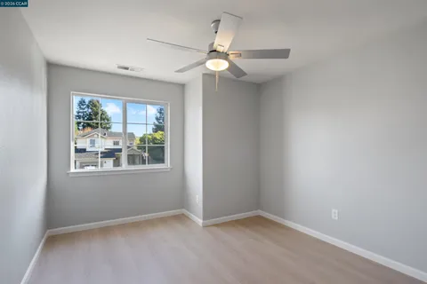 an empty room with windows and fan