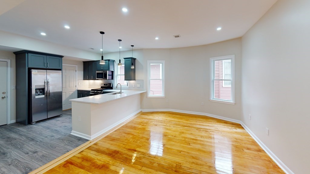 109 Deering Road, Unit 1 Boston, MA 02126 - Photo 3 of 12 a large kitchen with a center island wooden floor stainless steel appliances and windows
