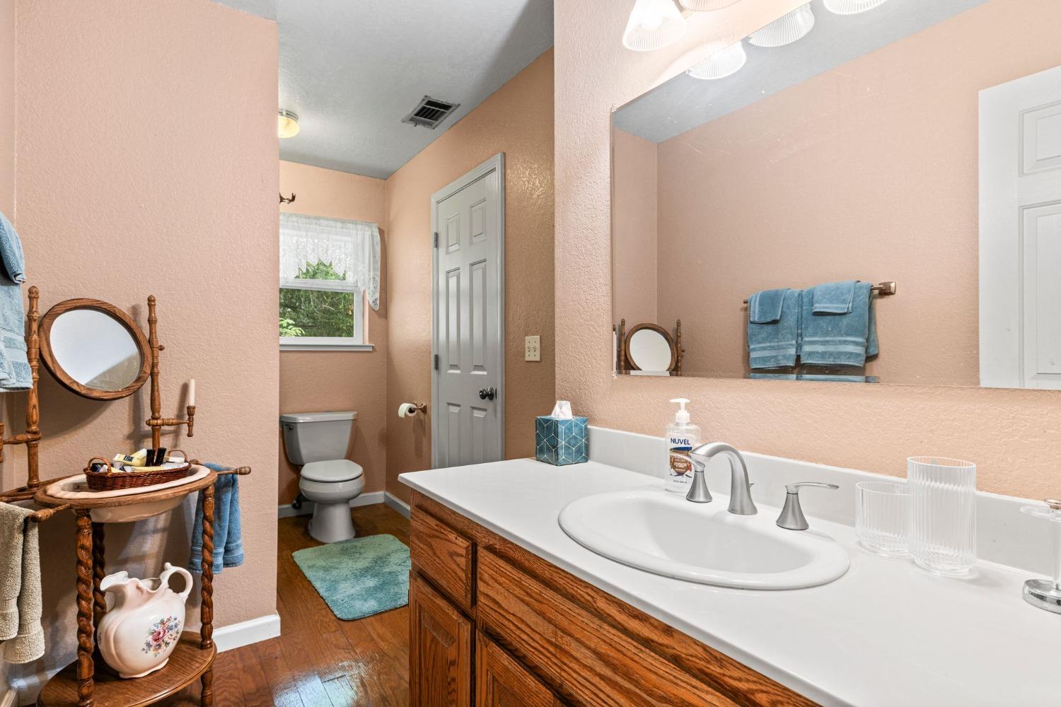 6432 Happy Valley Road Somerset, CA 95684 - Photo 64 of 90 a bathroom with a granite countertop toilet a sink and a mirror