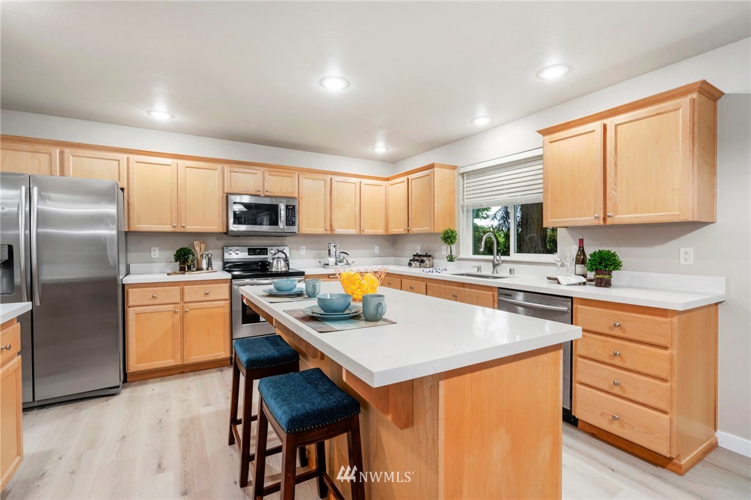 6719 Southeast 5th Street Renton, WA 98059 - Photo 8 of 29 a kitchen with granite countertop stainless steel appliances a refrigerator a stove a sink dishwasher and white cabinets with wooden floor