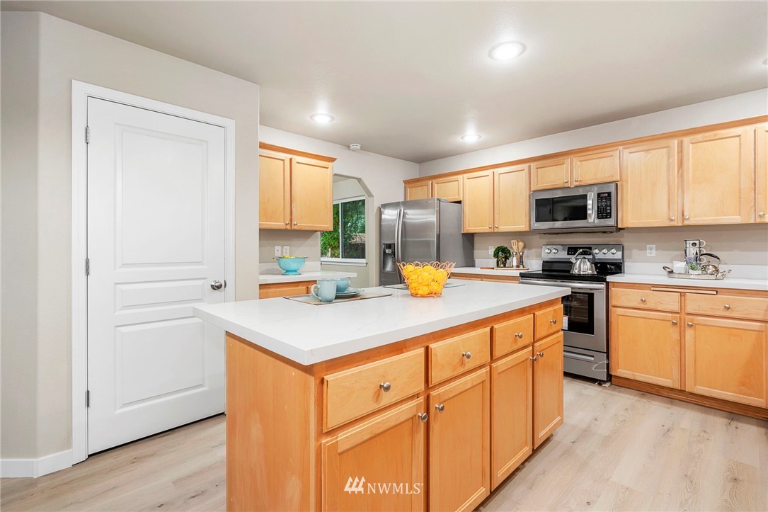 6719 Southeast 5th Street Renton, WA 98059 - Photo 10 of 29 a kitchen with stainless steel appliances granite countertop a stove top oven a sink dishwasher and a refrigerator with wooden floor