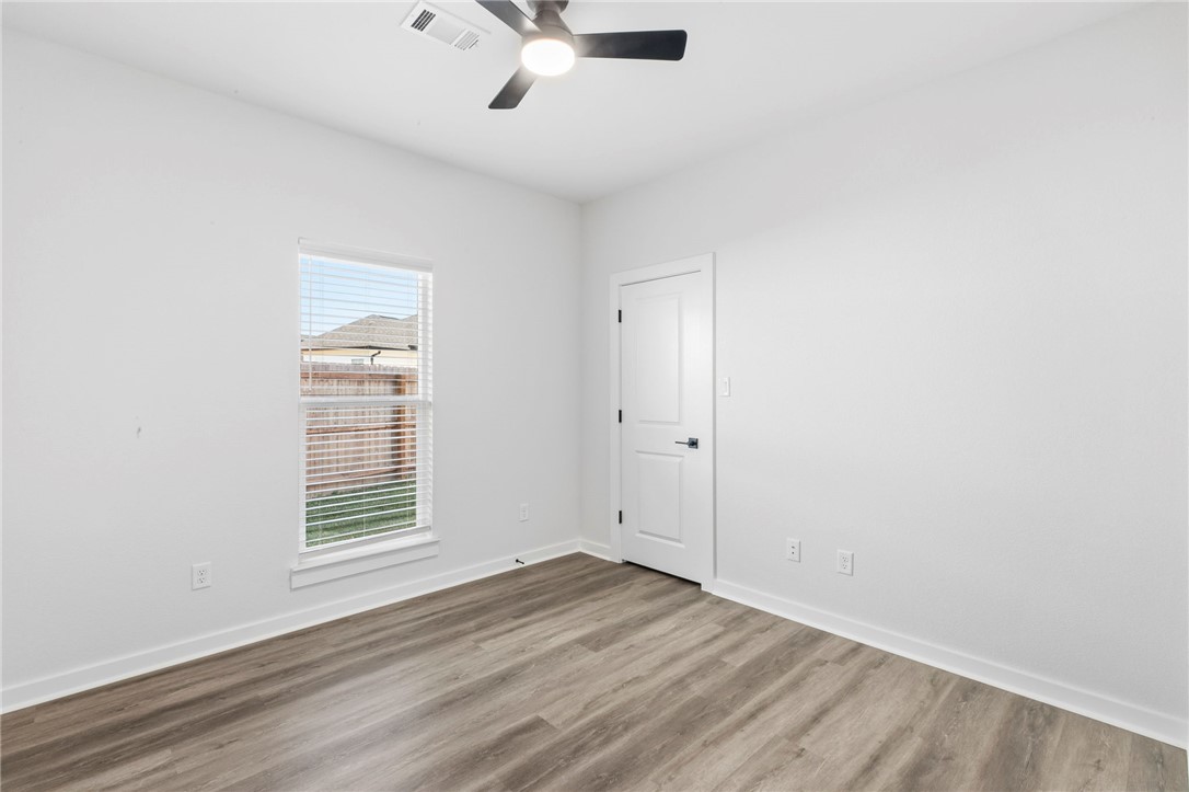 2102 Joppi Court Bryan, TX 77807 - Photo 15 of 27 an empty room with wooden floor chandelier fan and windows