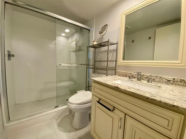 a bathroom with a granite countertop sink toilet and shower