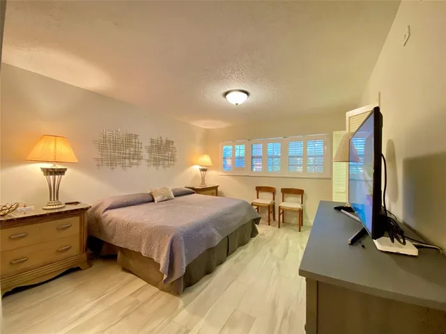 a bedroom with a bed and large flat tv screen on the dresser