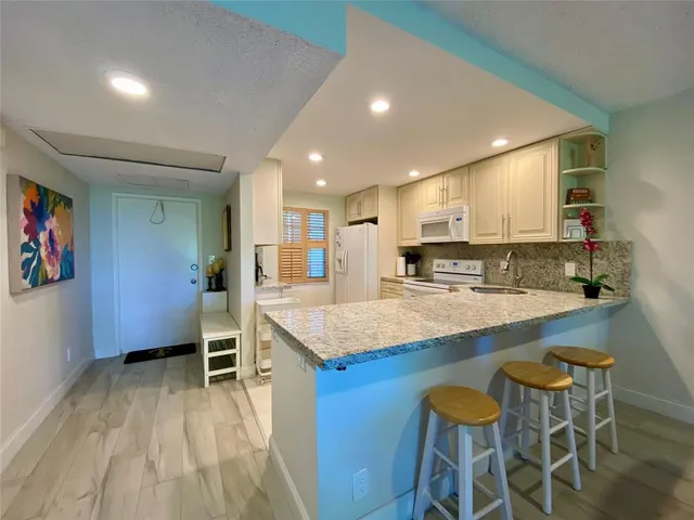 a kitchen with stainless steel appliances granite countertop a table chairs sink and cabinets
