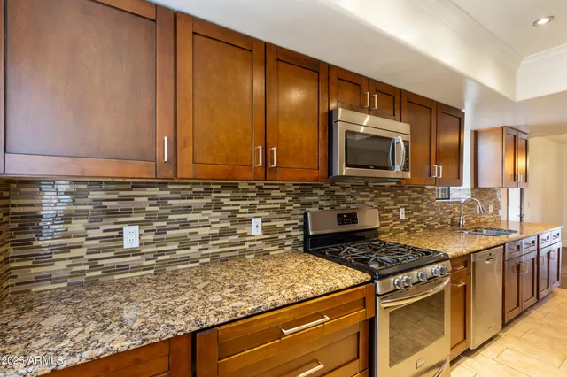 a kitchen with granite countertop cabinets stainless steel appliances and a sink