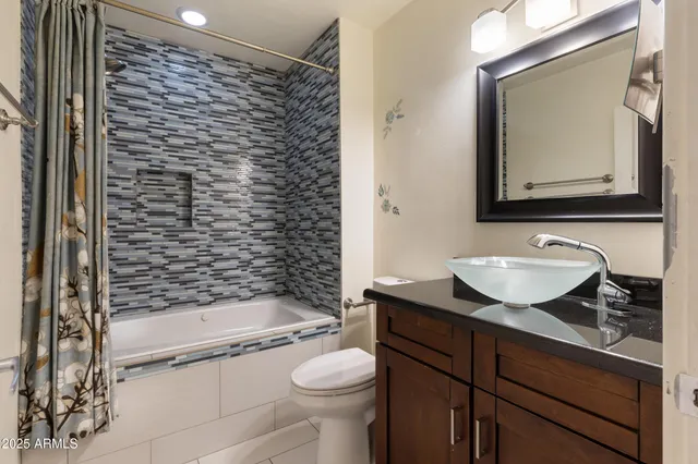 a bathroom with a granite countertop sink a toilet a mirror and shower