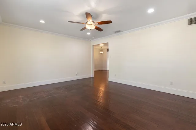an empty room with wooden floor and a ceiling fan