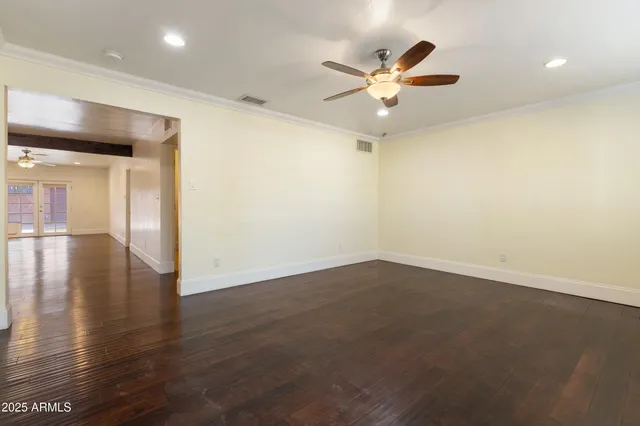 an empty room with wooden floor and a ceiling fan