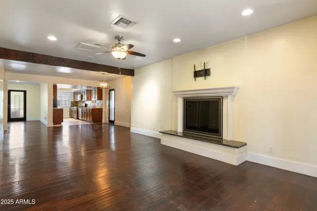 a view of an empty room with wooden floor fireplace and a window