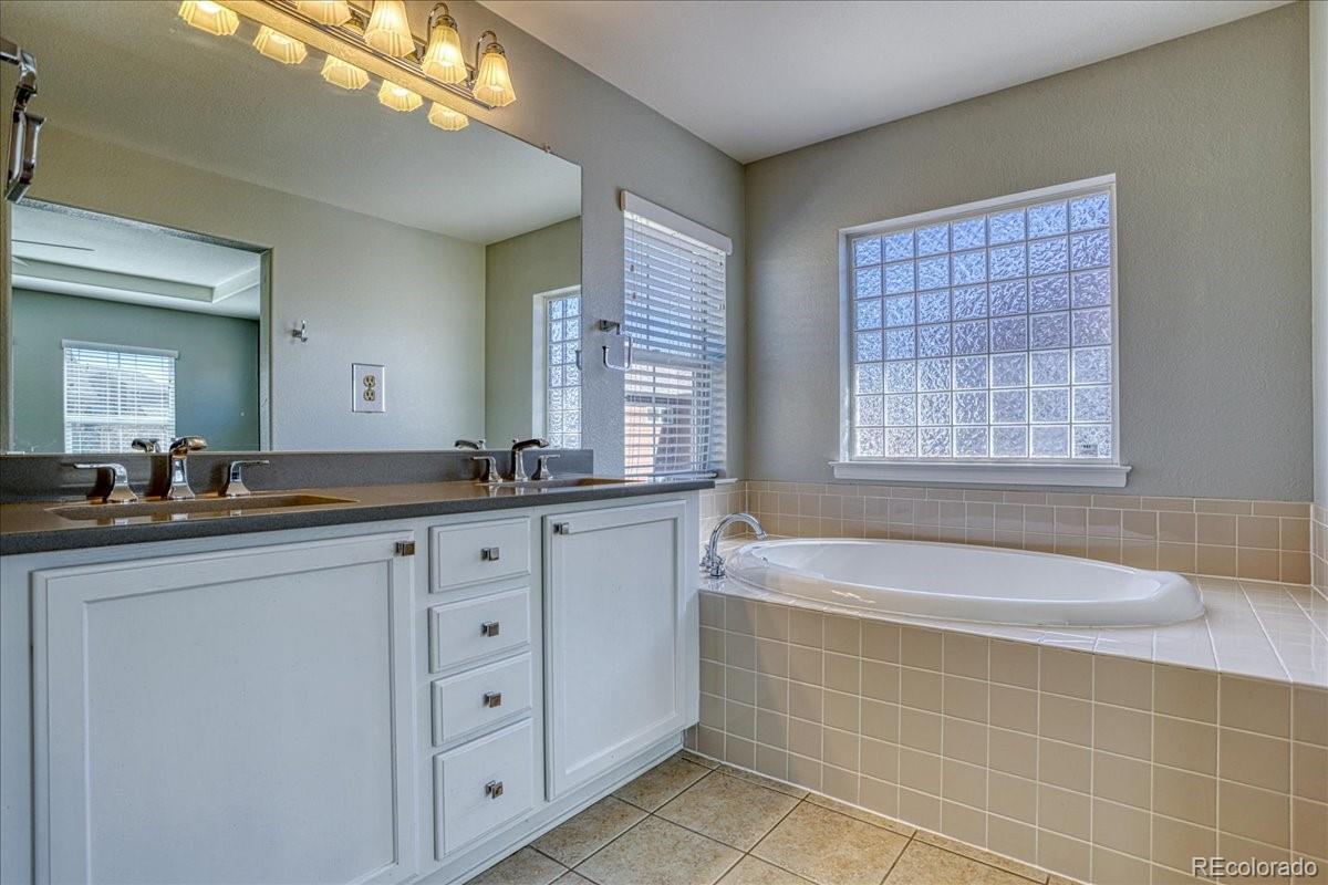 4005 Blue Pine Circle Highlands Ranch, CO 80126 - Photo 18 of 27 a spacious bathroom with a granite countertop tub a double vanity sink a vanity and a large mirror