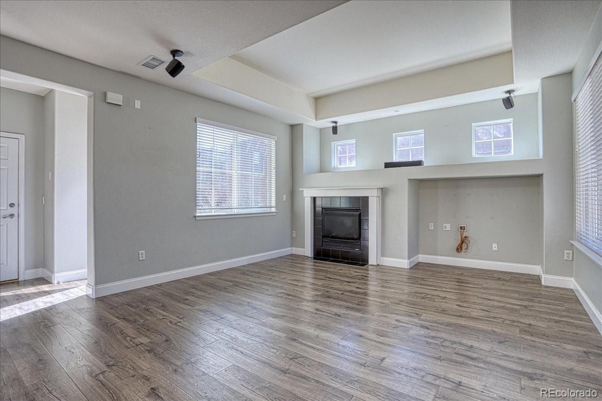 4005 Blue Pine Circle Highlands Ranch, CO 80126 - Photo 4 of 27 an empty room with wooden floor fireplace and windows