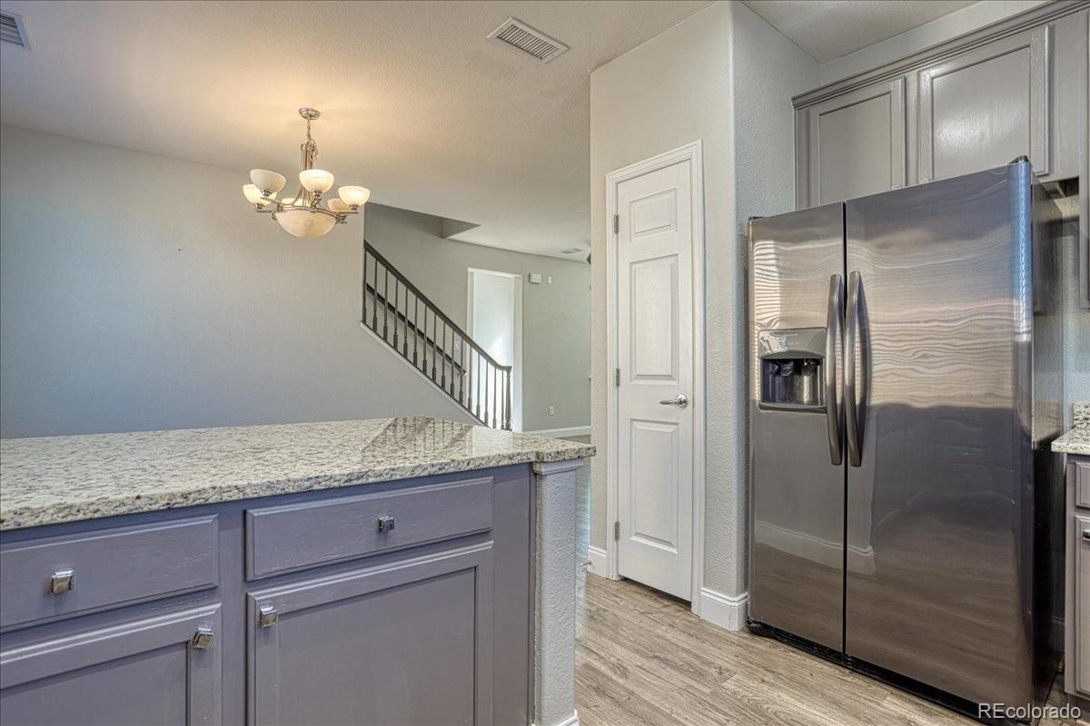 4005 Blue Pine Circle Highlands Ranch, CO 80126 - Photo 9 of 27 a hallway with granite countertop a refrigerator a sink and dishwasher