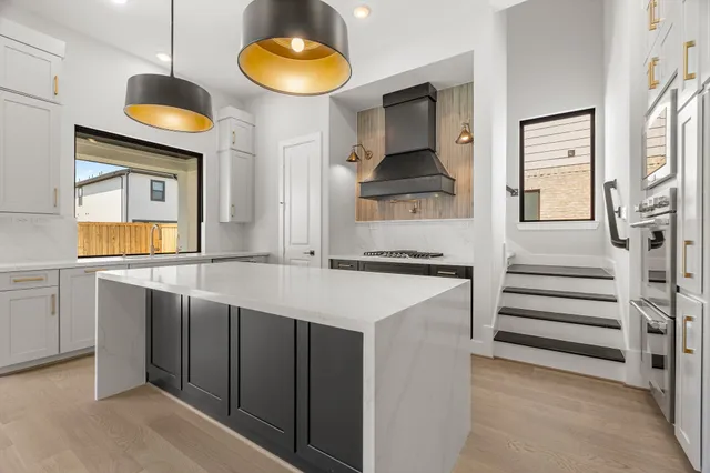 a kitchen with stainless steel appliances a stove a chimney and wooden floor