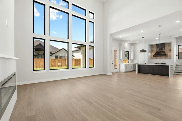 a view of an empty room with a window and kitchen view