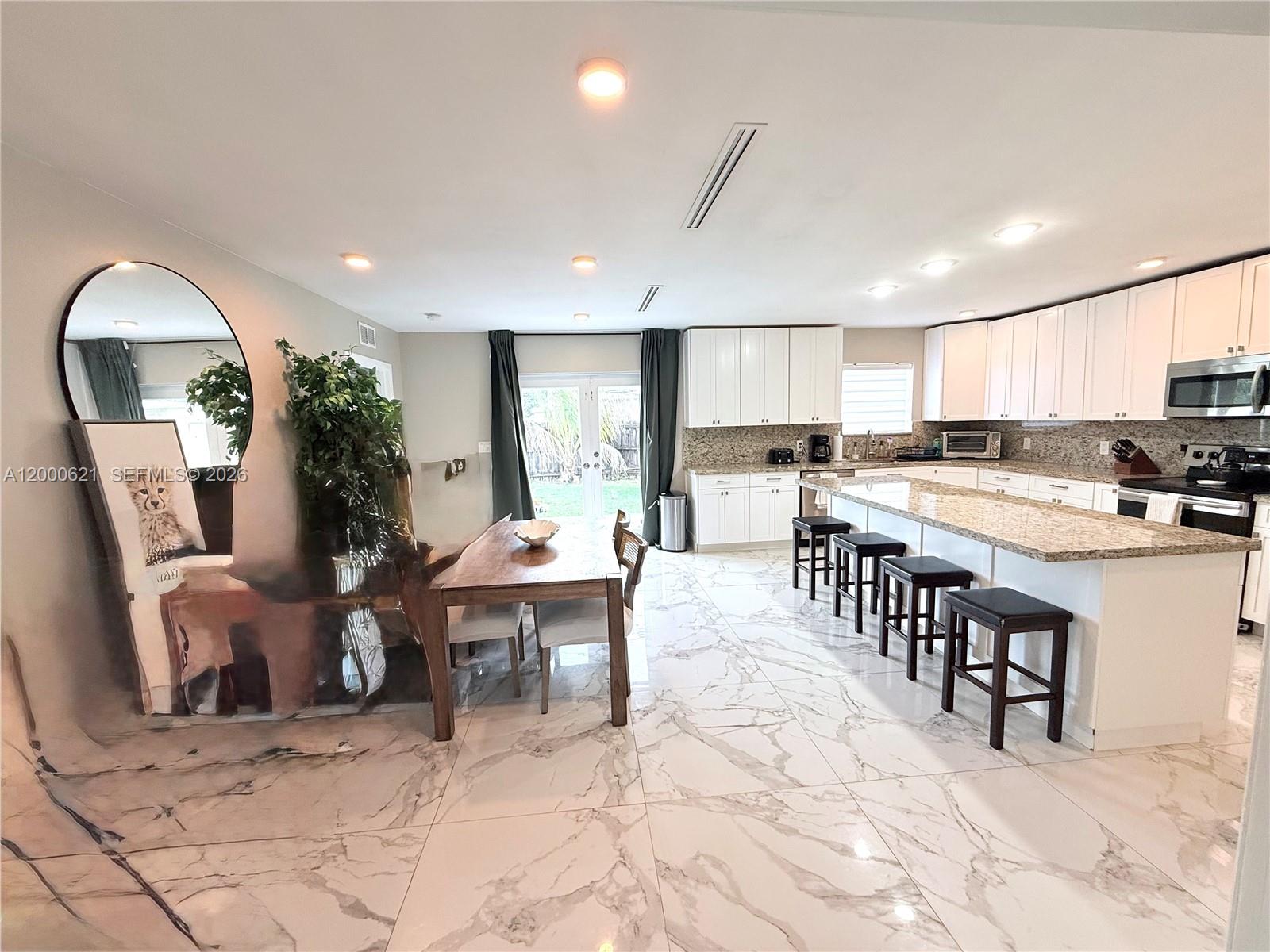 11020 Southwest 42nd Terrace Miami, FL 33165 - Photo 3 of 22 a kitchen with stainless steel appliances kitchen island granite countertop a stove a sink a dining table and chairs