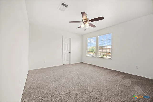 an empty room with windows and fan