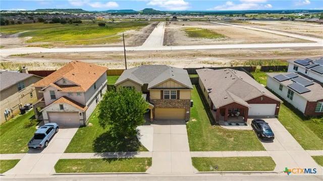 an aerial view of residential houses with outdoor space and parking