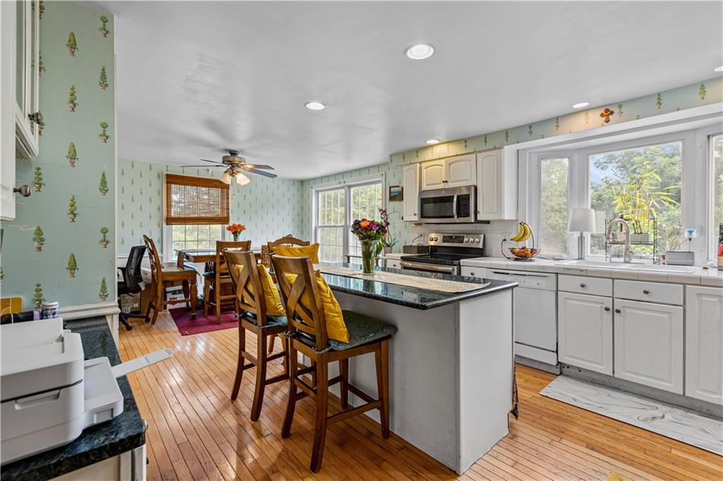 2116 Ramsey Road Monroeville, PA 15146 - Photo 10 of 28 a kitchen with stainless steel appliances granite countertop a stove top oven a sink a dining table and chairs with wooden floor