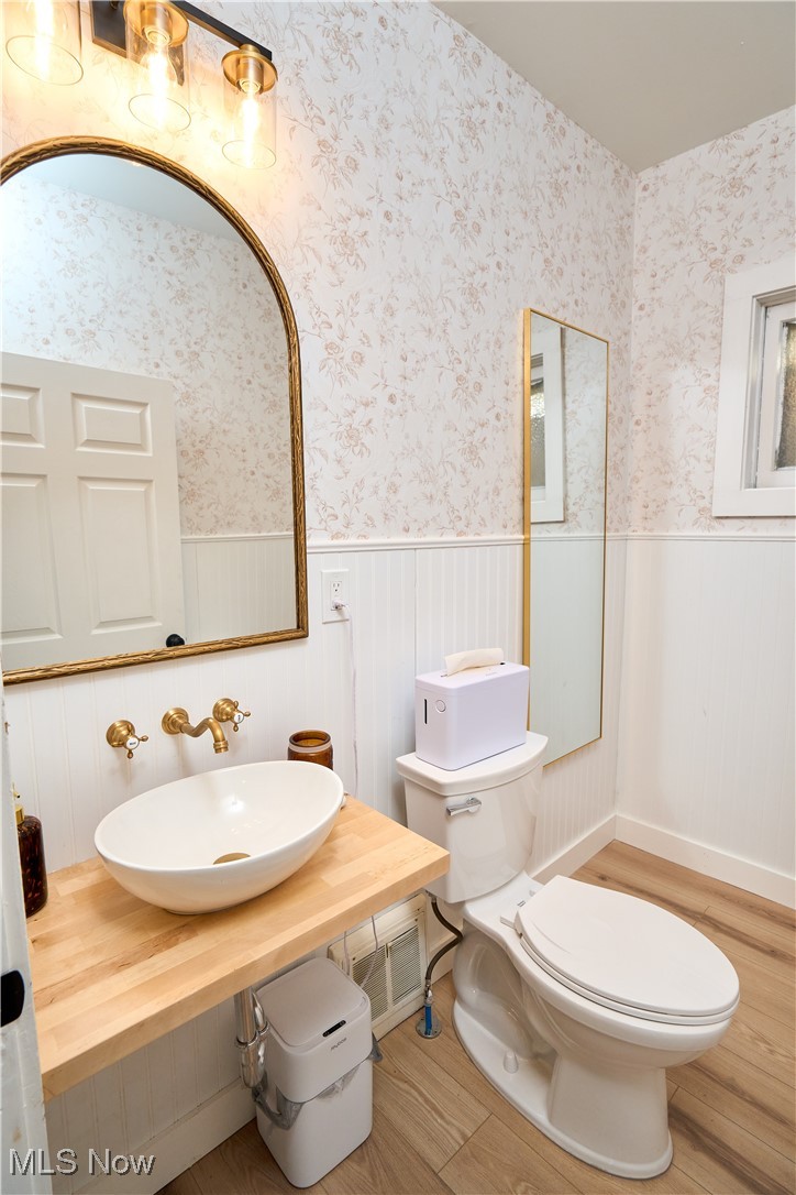 5432 State Road Parma, OH 44134 - Photo 13 of 47 Half bathroom with wainscoting, wood finished floors, and wallpapered walls