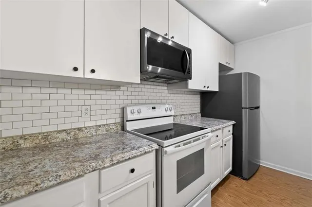 a kitchen with granite countertop white cabinets and stainless steel appliances